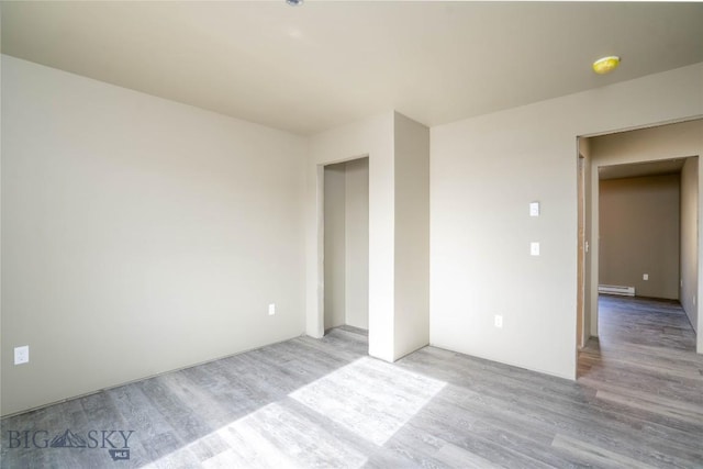 empty room with baseboard heating and light wood-style floors