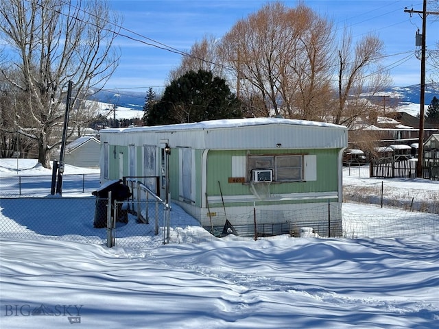 snow covered structure featuring a gate and fence