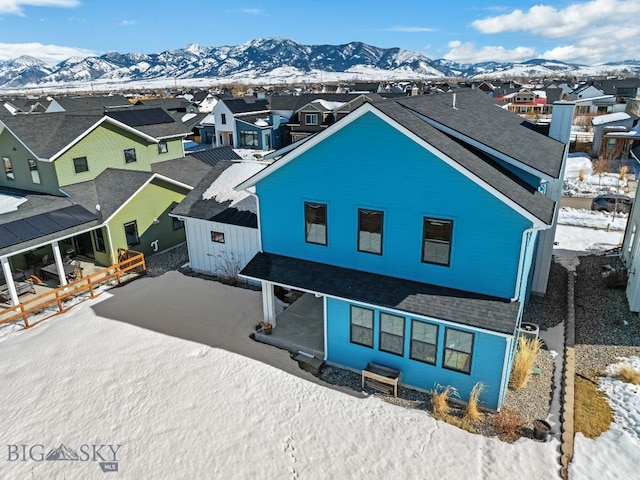 exterior space with a residential view, roof with shingles, and a mountain view