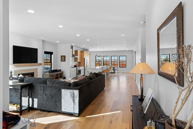 living area featuring a lit fireplace, light wood-style flooring, and recessed lighting