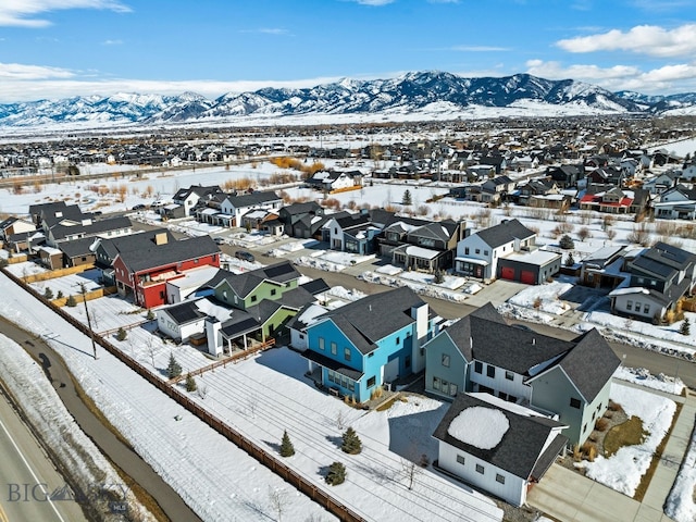 snowy aerial view featuring a mountain view and a residential view