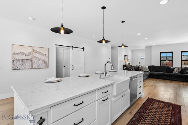 kitchen featuring a barn door, recessed lighting, a sink, white cabinetry, and light wood finished floors