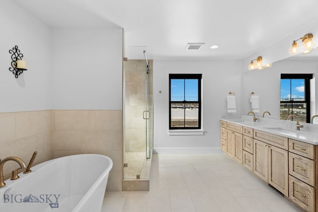 bathroom with double vanity, a freestanding tub, a sink, and visible vents