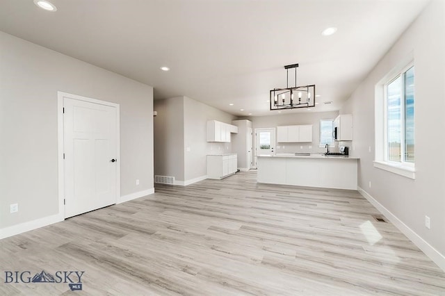 kitchen featuring light wood-type flooring, open floor plan, white cabinetry, and baseboards