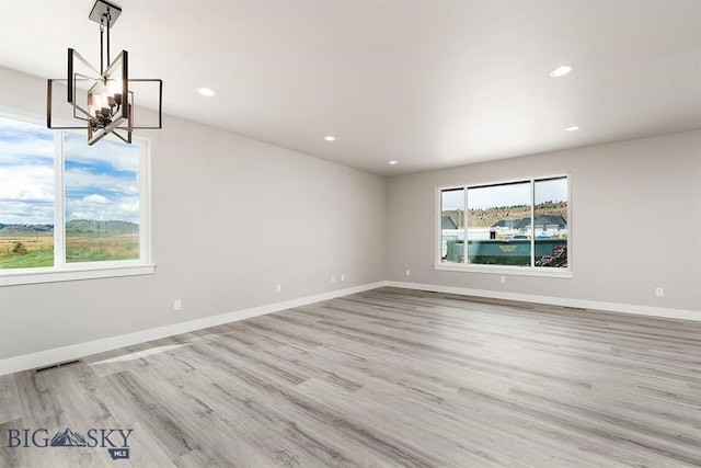 unfurnished room with a notable chandelier, recessed lighting, wood finished floors, visible vents, and baseboards