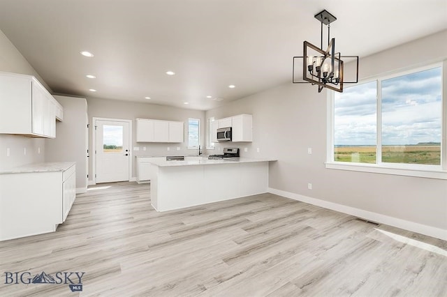 kitchen featuring baseboards, visible vents, a peninsula, stainless steel appliances, and light countertops