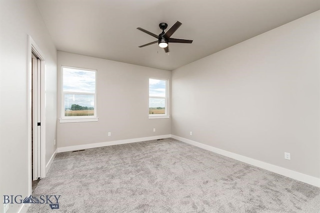 spare room with carpet flooring, ceiling fan, visible vents, and baseboards