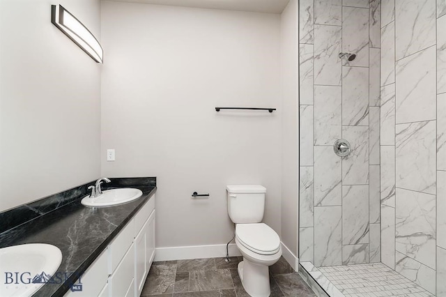 bathroom with toilet, a sink, baseboards, tiled shower, and double vanity