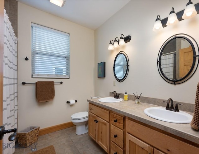 full bath featuring double vanity, a sink, toilet, and tile patterned floors