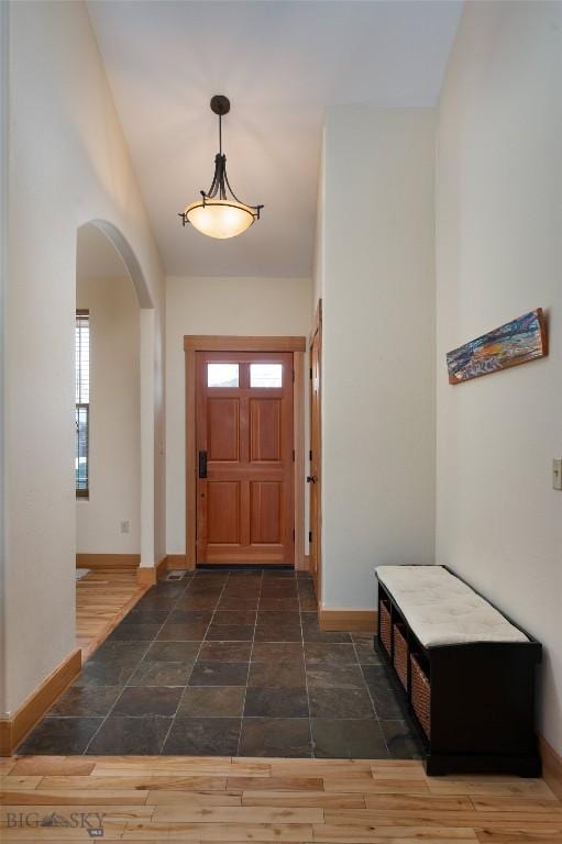 foyer featuring dark wood-style floors, baseboards, a high ceiling, and arched walkways