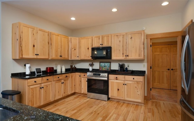 kitchen with light wood-style flooring, recessed lighting, appliances with stainless steel finishes, light brown cabinetry, and dark stone countertops