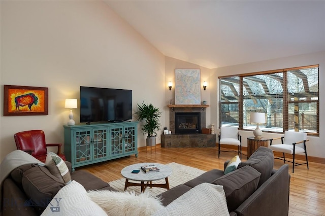 living area featuring high vaulted ceiling, a fireplace, and wood finished floors