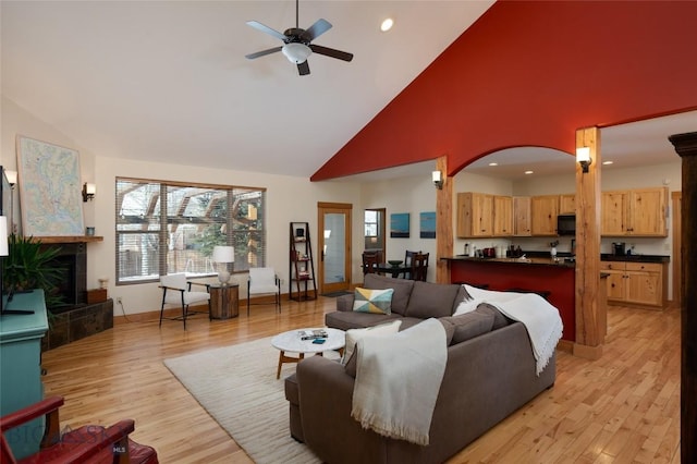 living room featuring light wood-style floors, a fireplace, high vaulted ceiling, and recessed lighting