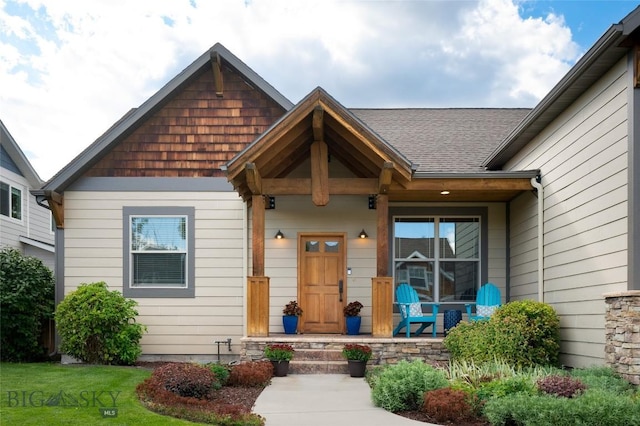 doorway to property featuring a yard and roof with shingles