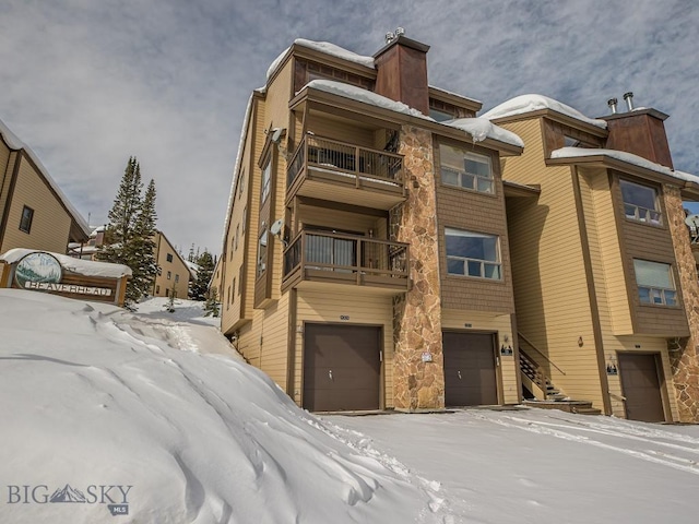 snow covered property featuring an attached garage