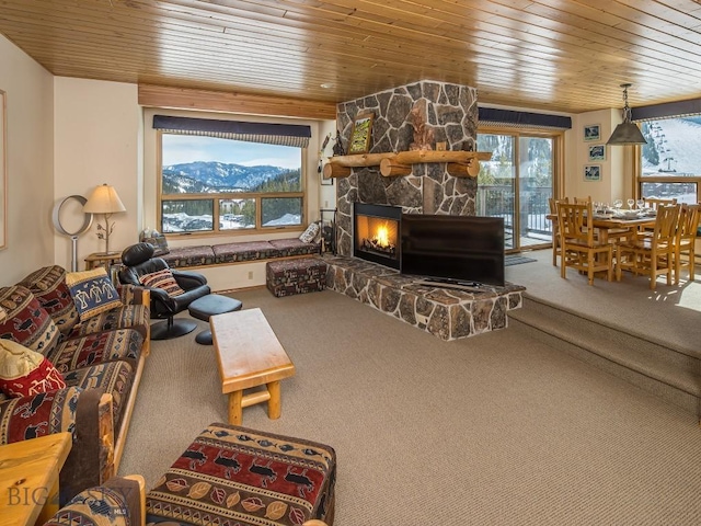 living area featuring wooden ceiling, carpet flooring, a mountain view, and a stone fireplace