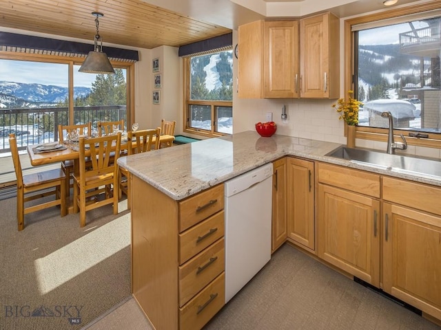 kitchen featuring decorative light fixtures, backsplash, white dishwasher, a sink, and a peninsula