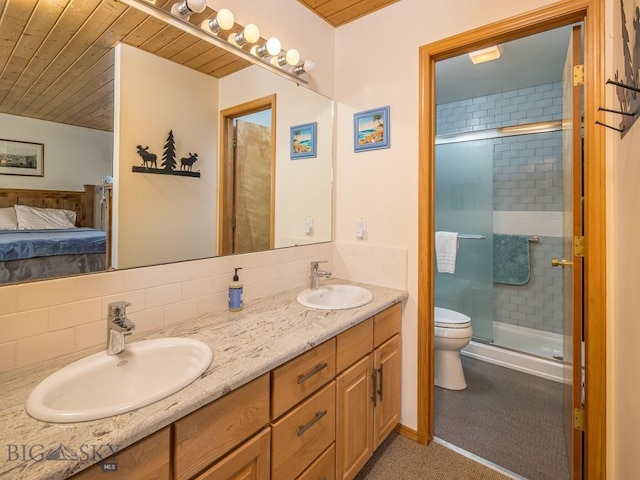 full bath featuring a sink, a shower stall, toilet, and double vanity