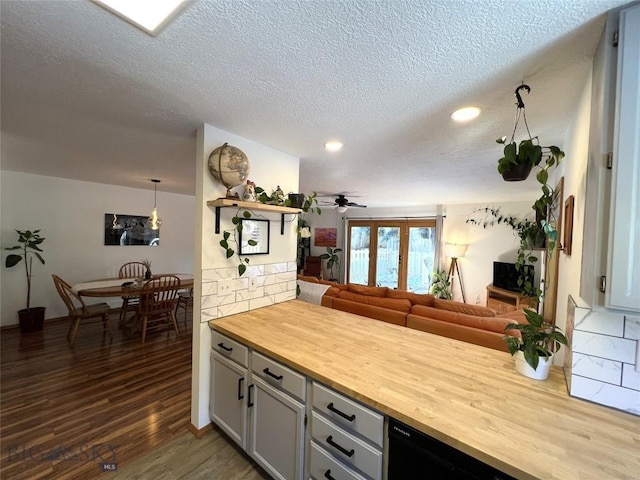 kitchen featuring butcher block countertops, open floor plan, dark wood-type flooring, a peninsula, and a textured ceiling