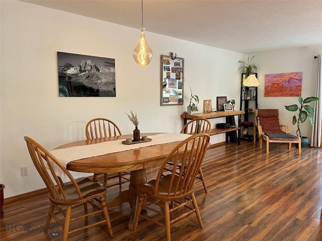 dining room with dark wood-style flooring, a textured ceiling, and baseboards