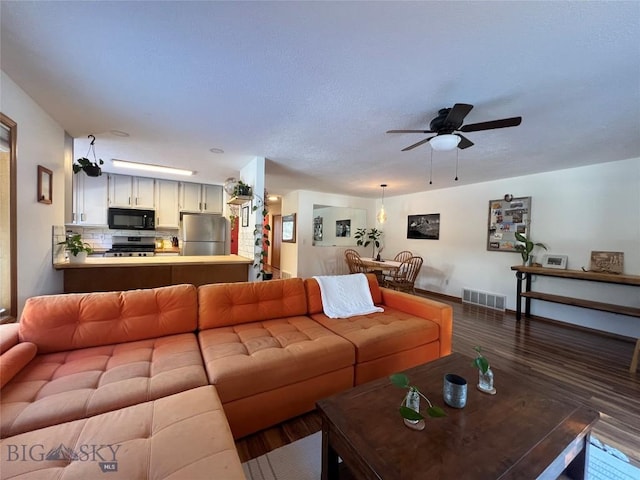 living area with visible vents, ceiling fan, and wood finished floors