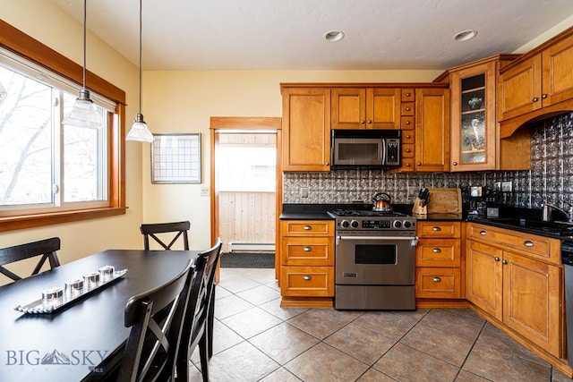 kitchen with a baseboard heating unit, a sink, appliances with stainless steel finishes, brown cabinets, and dark countertops