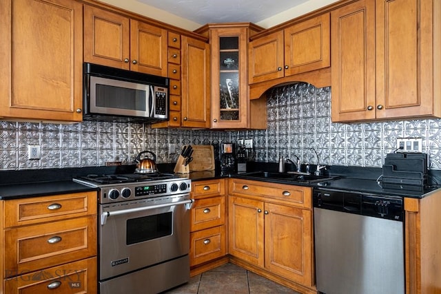 kitchen featuring brown cabinets, dark countertops, stainless steel appliances, and a sink