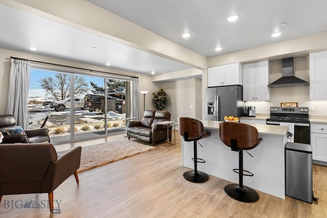 kitchen with stainless steel appliances, open floor plan, light countertops, and wall chimney range hood