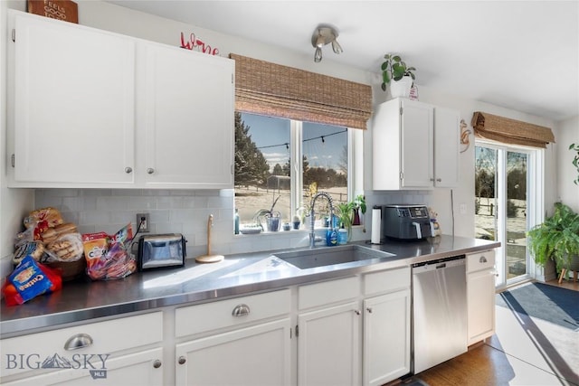 kitchen featuring stainless steel dishwasher, a sink, white cabinetry, and decorative backsplash