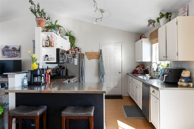 kitchen with a breakfast bar area, stainless steel counters, appliances with stainless steel finishes, vaulted ceiling, and a sink