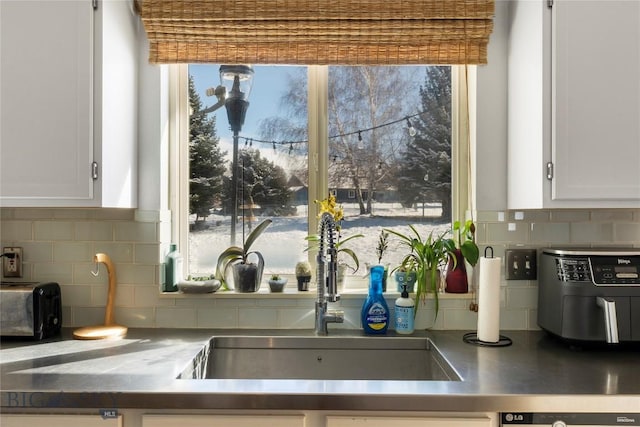 kitchen featuring plenty of natural light, white cabinetry, and a sink