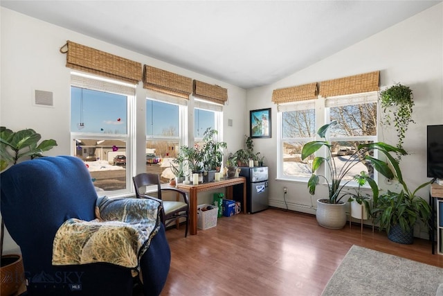 sitting room with lofted ceiling, plenty of natural light, wood finished floors, and visible vents