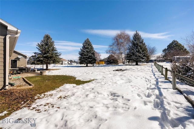 yard covered in snow with fence and a patio