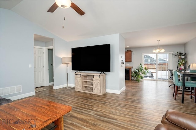 living area featuring lofted ceiling, ceiling fan with notable chandelier, wood finished floors, visible vents, and baseboards