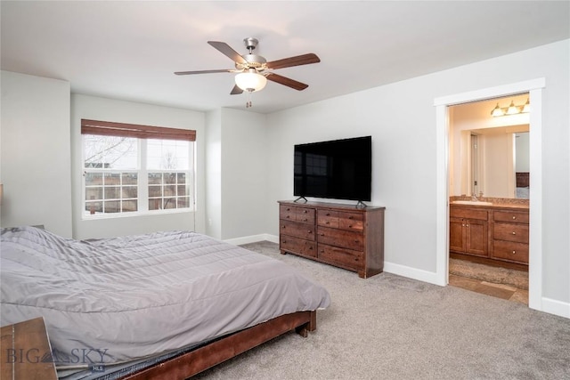 bedroom featuring light colored carpet, a sink, baseboards, and ceiling fan