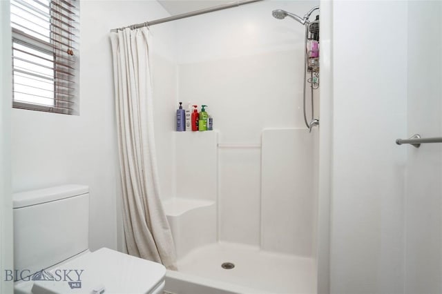 full bath featuring a shower stall and toilet