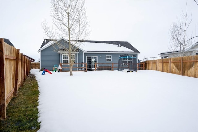 snow covered house featuring a fenced backyard and a wooden deck