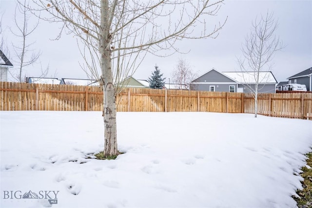 snowy yard featuring a fenced backyard