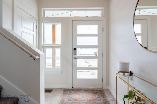 foyer featuring a healthy amount of sunlight, visible vents, baseboards, and stairs