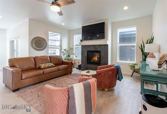 living area with light wood-type flooring, a tile fireplace, plenty of natural light, and recessed lighting