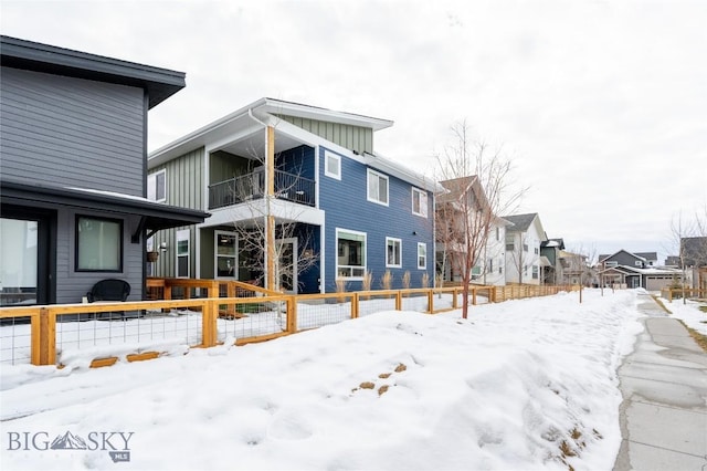 snow covered back of property featuring board and batten siding and a residential view