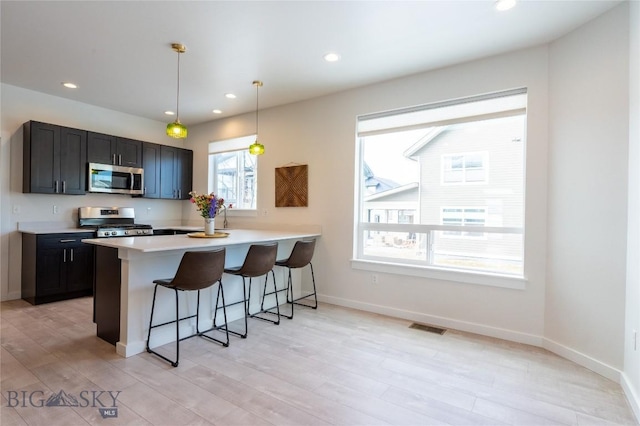 kitchen with visible vents, appliances with stainless steel finishes, a kitchen breakfast bar, light countertops, and recessed lighting