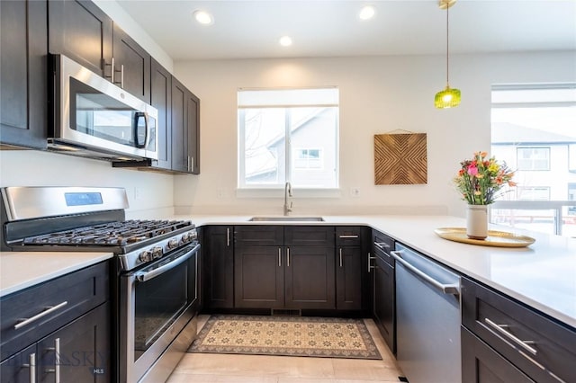 kitchen with appliances with stainless steel finishes, light countertops, a sink, and recessed lighting