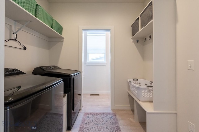 clothes washing area featuring laundry area, light tile patterned flooring, washing machine and clothes dryer, and baseboards