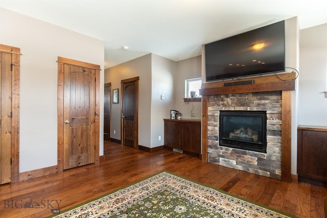 living room featuring a fireplace, baseboards, and wood finished floors