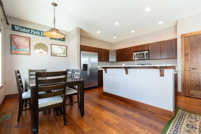 kitchen featuring visible vents, dark wood-style floors, appliances with stainless steel finishes, a breakfast bar area, and pendant lighting