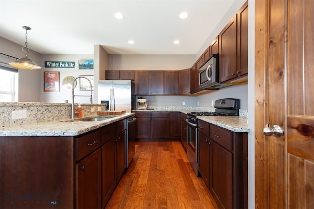 kitchen with decorative light fixtures, dark wood finished floors, stainless steel appliances, recessed lighting, and light stone countertops