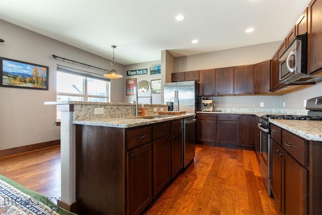 kitchen featuring a kitchen island with sink, appliances with stainless steel finishes, a sink, and wood finished floors