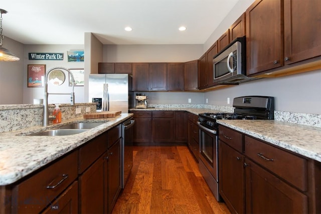 kitchen featuring wood finished floors, appliances with stainless steel finishes, a sink, and light stone countertops