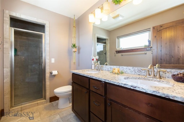 bathroom featuring toilet, a stall shower, double vanity, and a sink